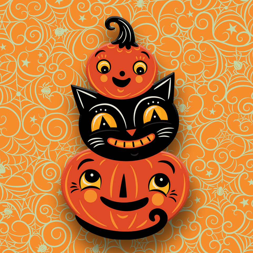 Three Halloween-themed pumpkins stacked on an orange patterned background Johanna Parker Halloween brooch