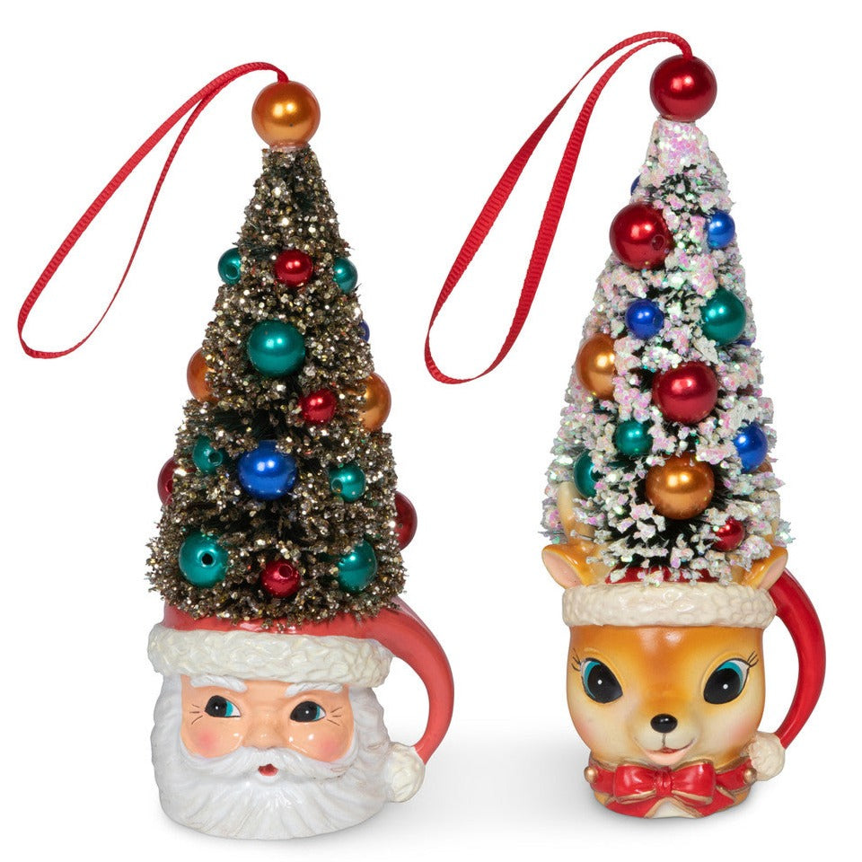 Two holiday-themed mug ornaments, one with a Santa face and the other with a deer, both topped with miniature sisal trees decorated with colorful ornaments and a red ribbon for hanging.