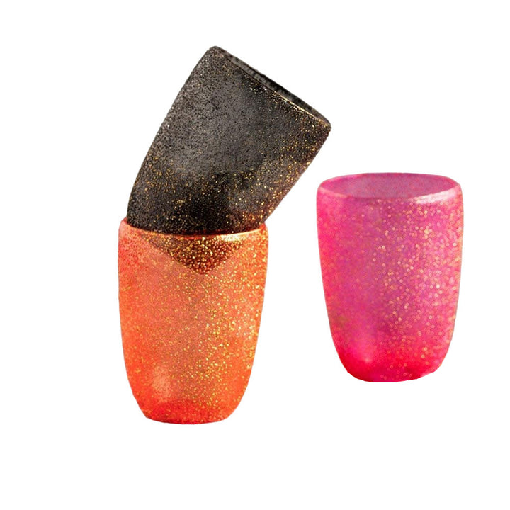 A set of three hand-blown, stubbled, glittered glass votive holders in black, orange, and pink colors.