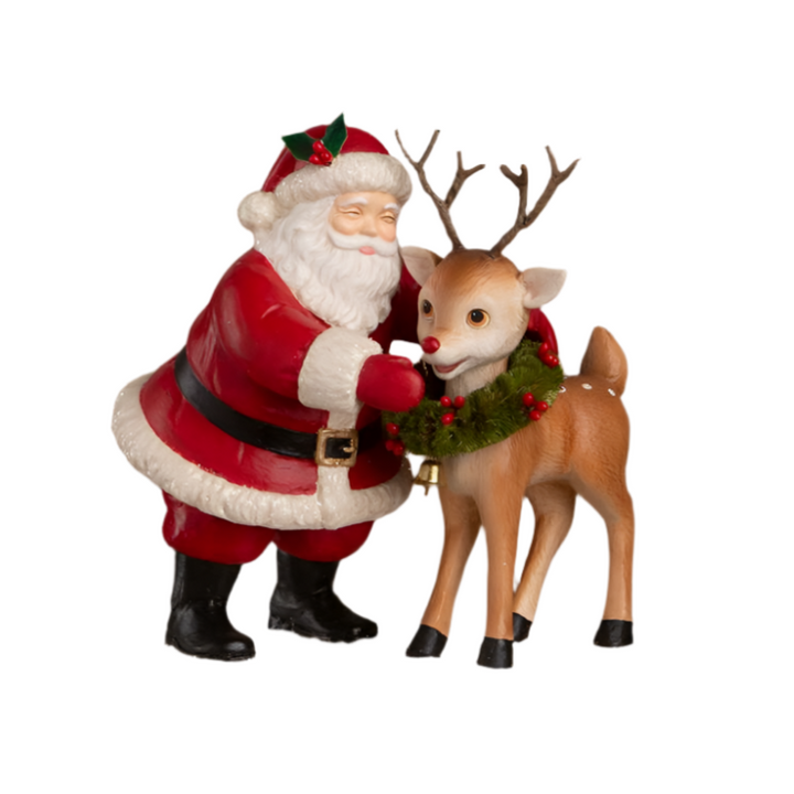 Bethany lowe hand-painted resin figurine of Santa Claus placing a green bottle brush wreath with red berries on a reindeer, with attention to detail in design.
