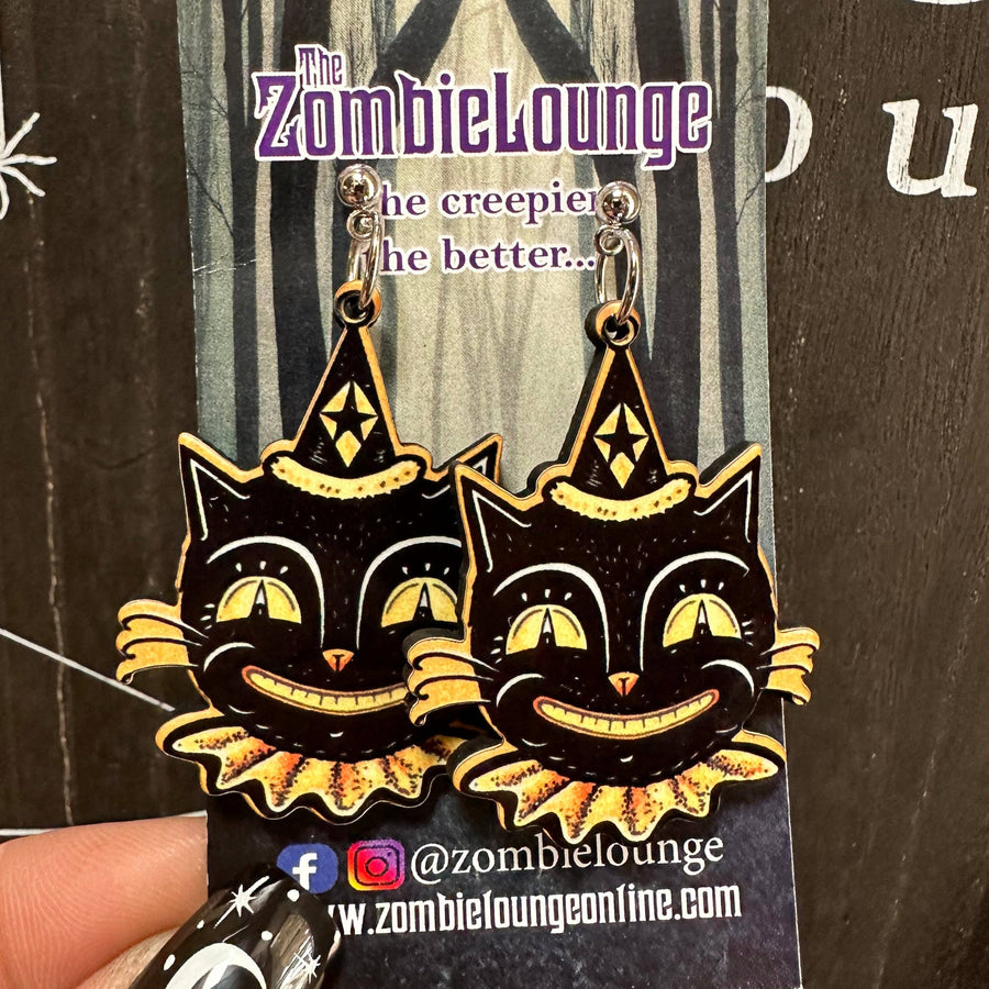 Black cat earrings with yellow accents on a Zombielounge branded card.