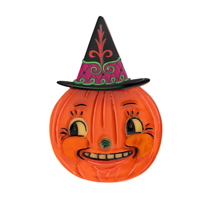 An orange pumpkin-shaped brooch with a whimsical face and a black and pink witch's hat, crafted from resin.