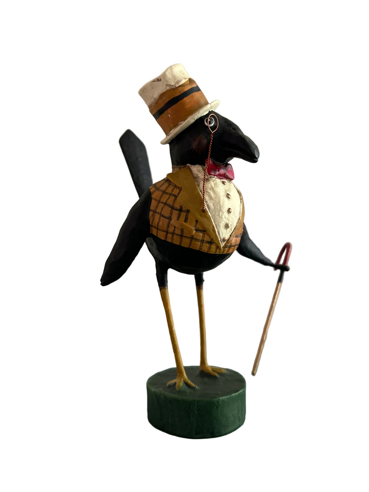 A decorative raven figurine dressed in vintage attire, including a cream top hat with a brown band, a yellow vest, a red bow tie, and a cane, standing on a round green base against a plain white background.