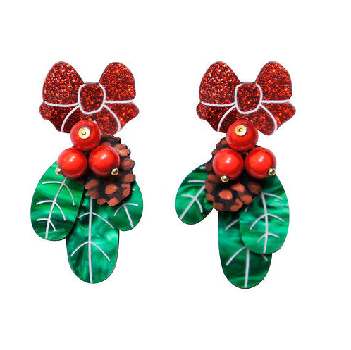 Pair of festive earrings with red bows, berries, and green leaves on a white background