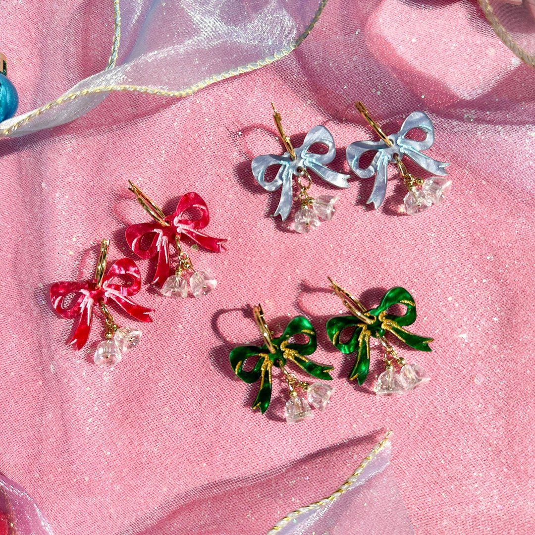 Colorful bow-shaped earrings on a pink fabric background