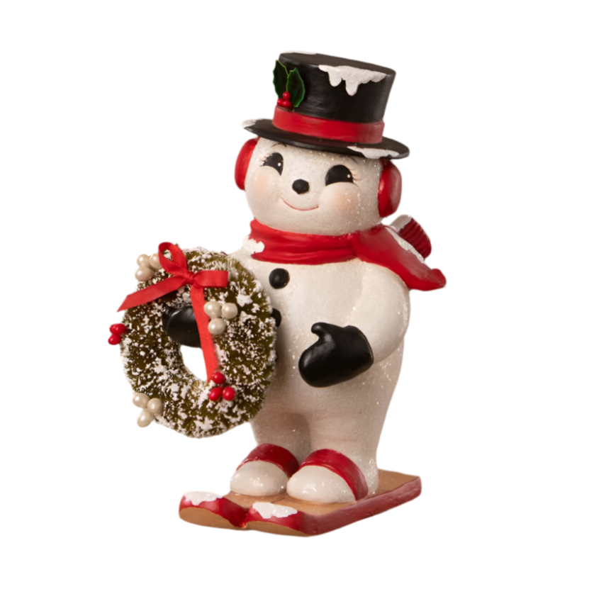 Bethany lowe christmas snowman hand-painted resin snowman figurine with a black top hat, red scarf, carrying a bottle brush wreath, and standing on a red and green base.