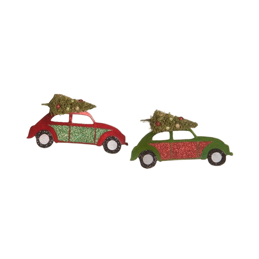 Two hand-painted tin ornaments shaped like vintage cars with Christmas trees on the roof, decorated with metallic red and green paint, glitter, and bottle brush trees.