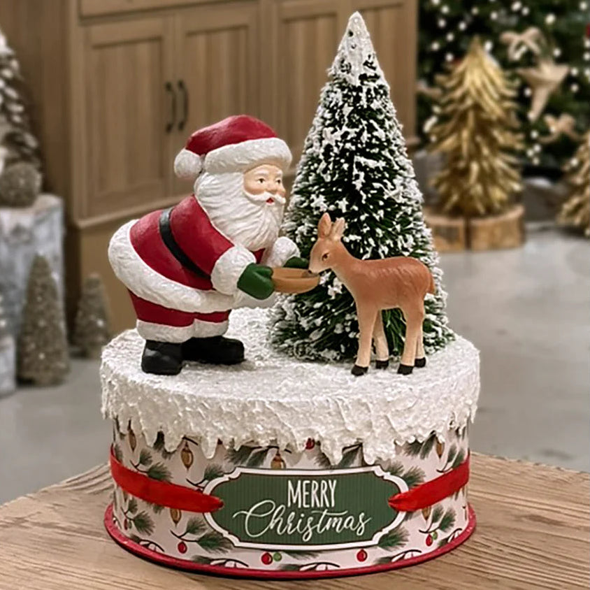 bethany lowe Christmas-themed cake with Santa Claus and reindeer figurines in a decorated room.