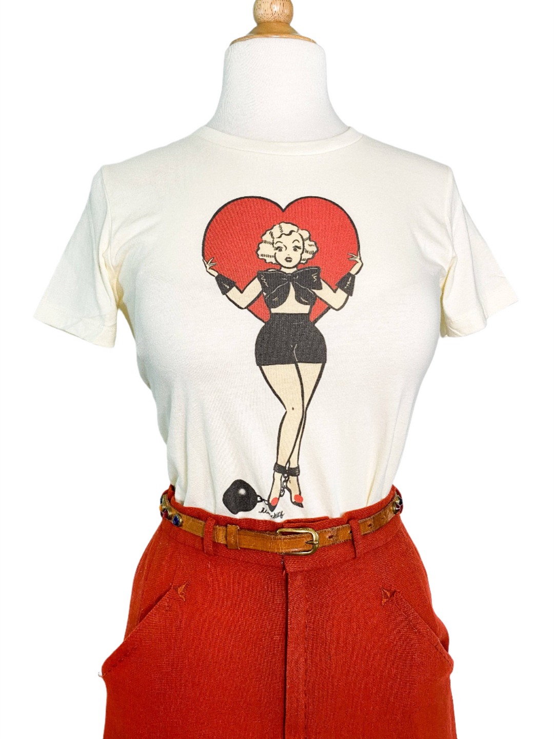 A fitted tee in ivory color with a digital print of a character standing inside a heart shape.