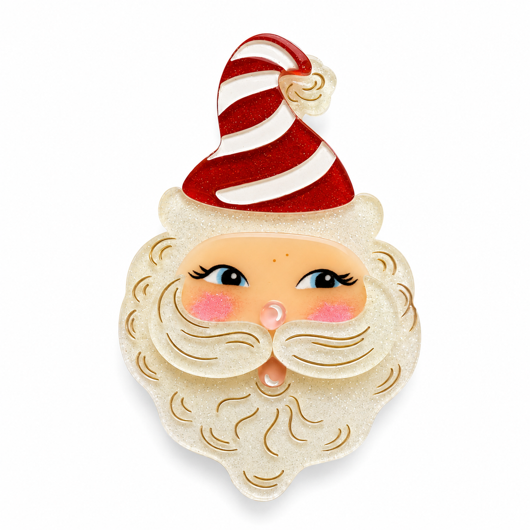 A festive Santa Claus face brooch featuring a glittery cream beard, blue eyes, pink cheeks, and a red and white striped hat by lipstick and chrome